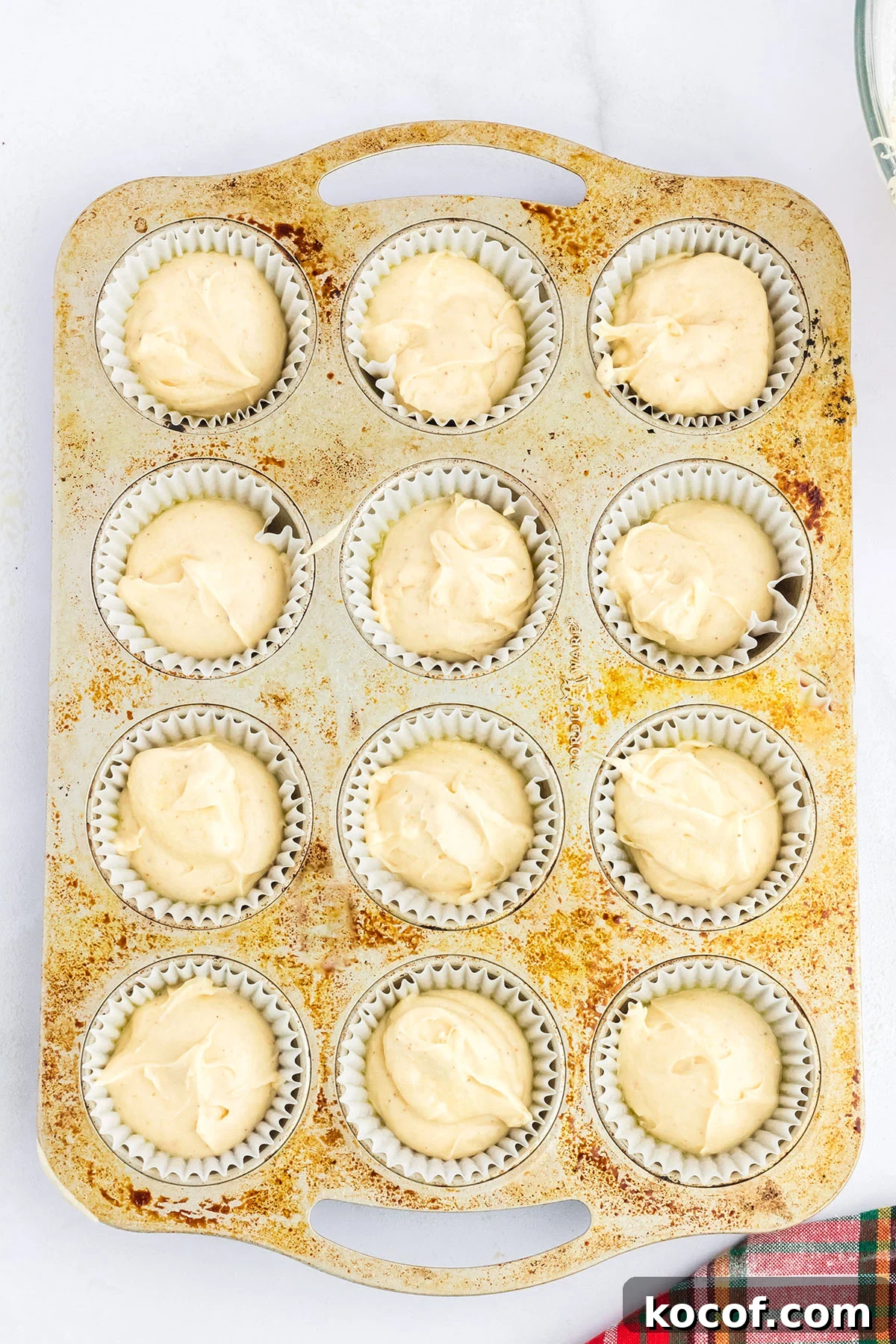 Eggnog cupcake batter scooped into a muffin pan.