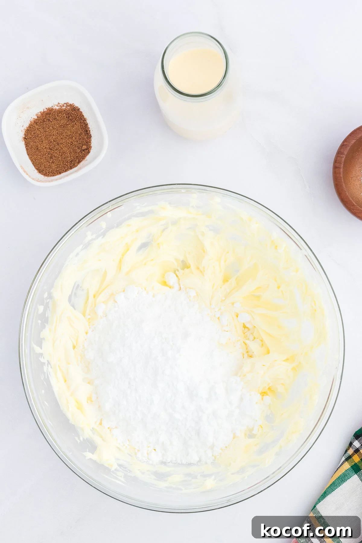 Beaten butter and powdered sugar in a glass mixing bowl.