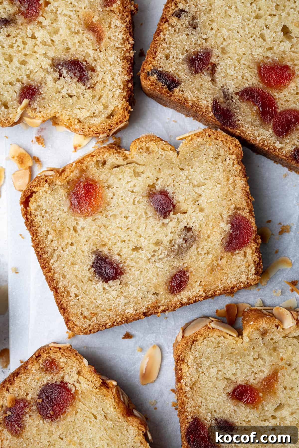 Slices of vegan cherry almond cake on a sheet of white baking paper.