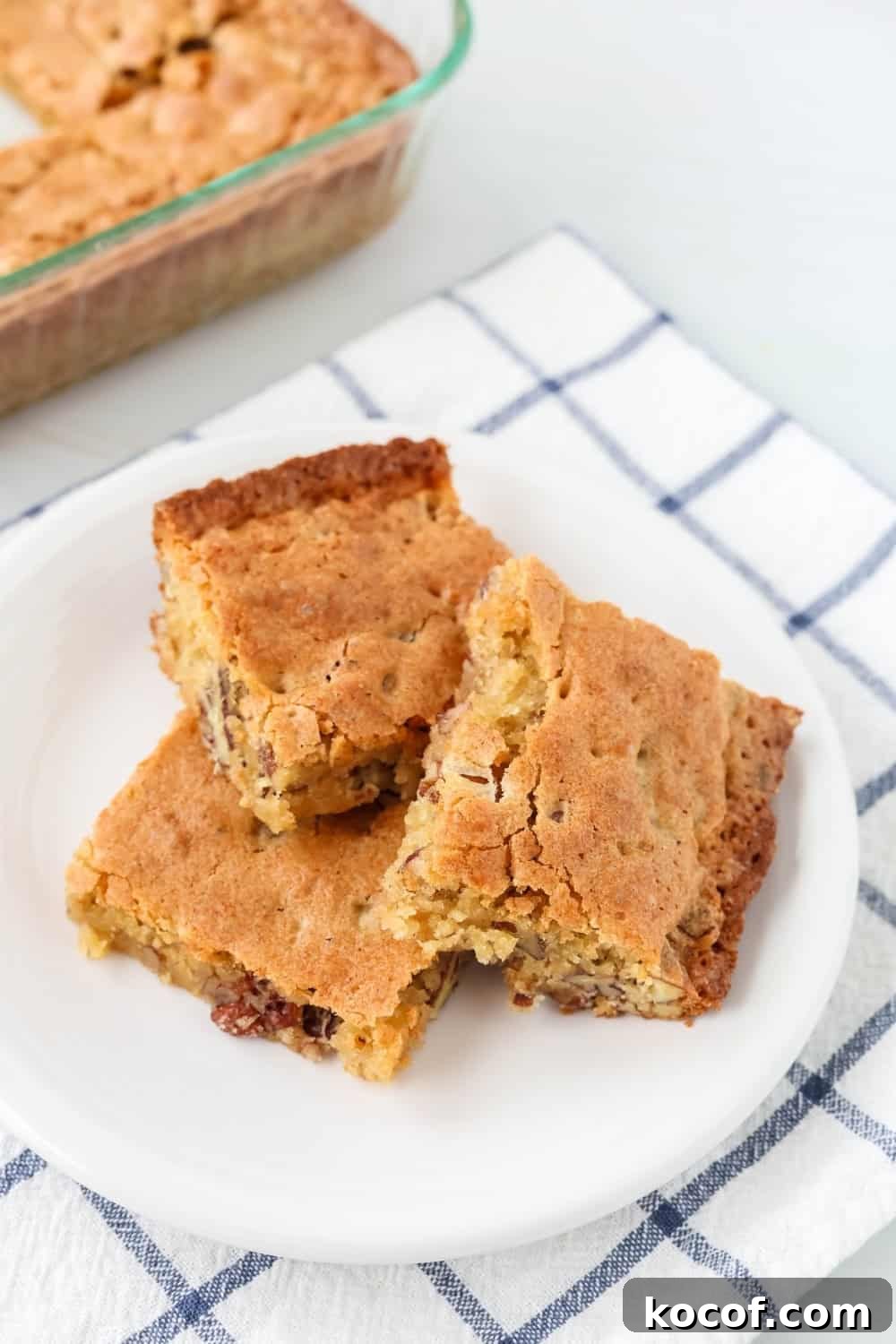 Southern Pecan Quick-Bread Recipe with Brown Sugar Glaze 3 a white plate serves squares of sweet Alabama pecan bread, with the remaining pan of bread in the background.