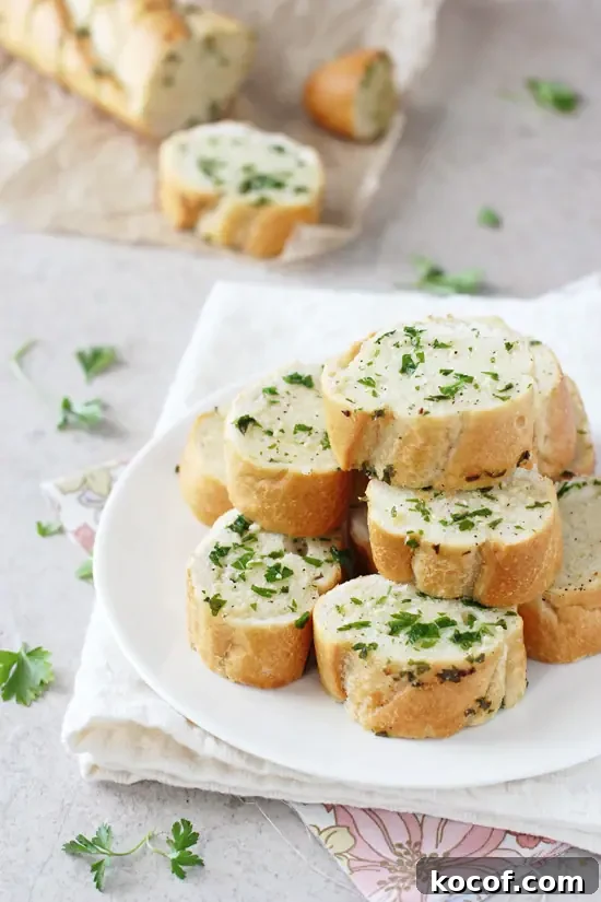 Easy, fast and delicious homemade freezer garlic bread! Have this crispy, herby and buttery bread ready to go whenever you need it! Slices of Homemade Freezer Garlic Bread stacked on a white plate.