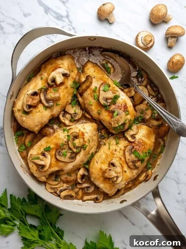 Top view of chicken marsala in a large skillet, topped with mushrooms and marsala wine sauce.