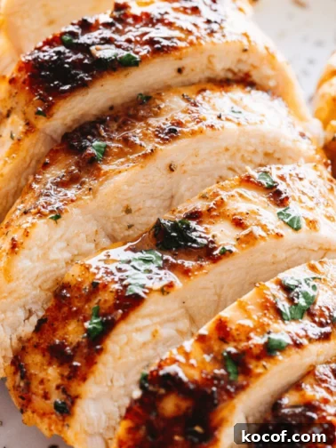 close up shot of juicy oven baked chicken breast cut into horizontal slices.
