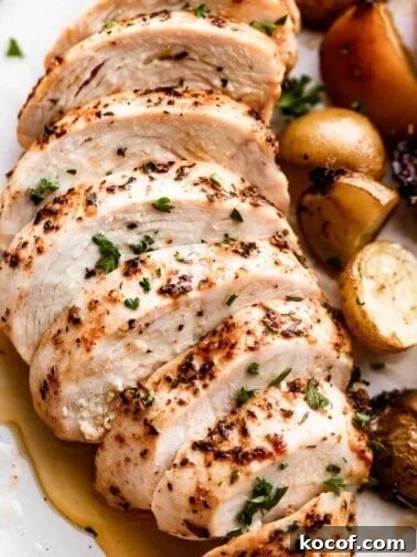 close up photo of slow cooker chicken breast, sliced and arranged on a white dinner plate.