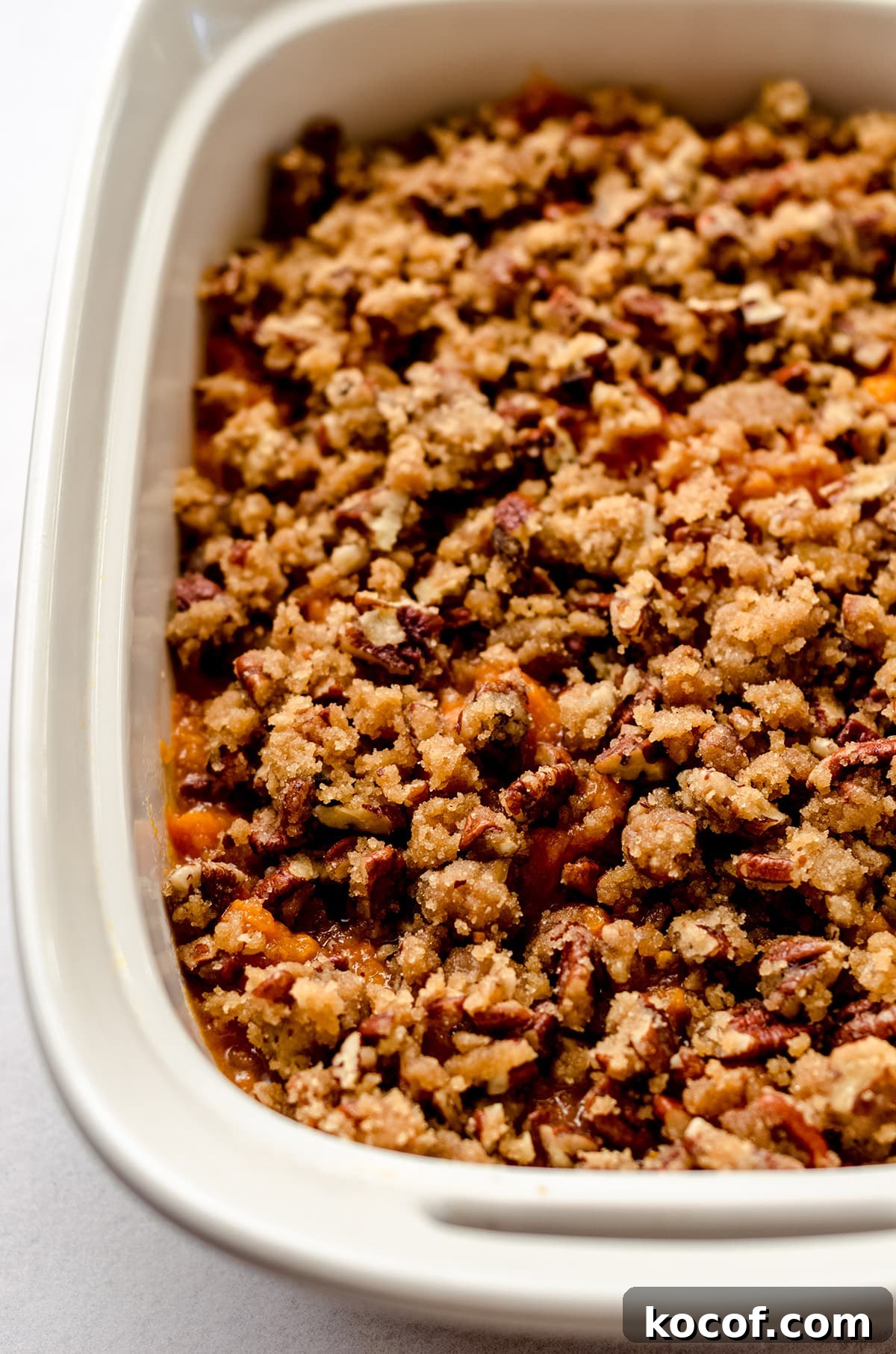 A baking dish full of sweet potato casserole, topped with pecans.