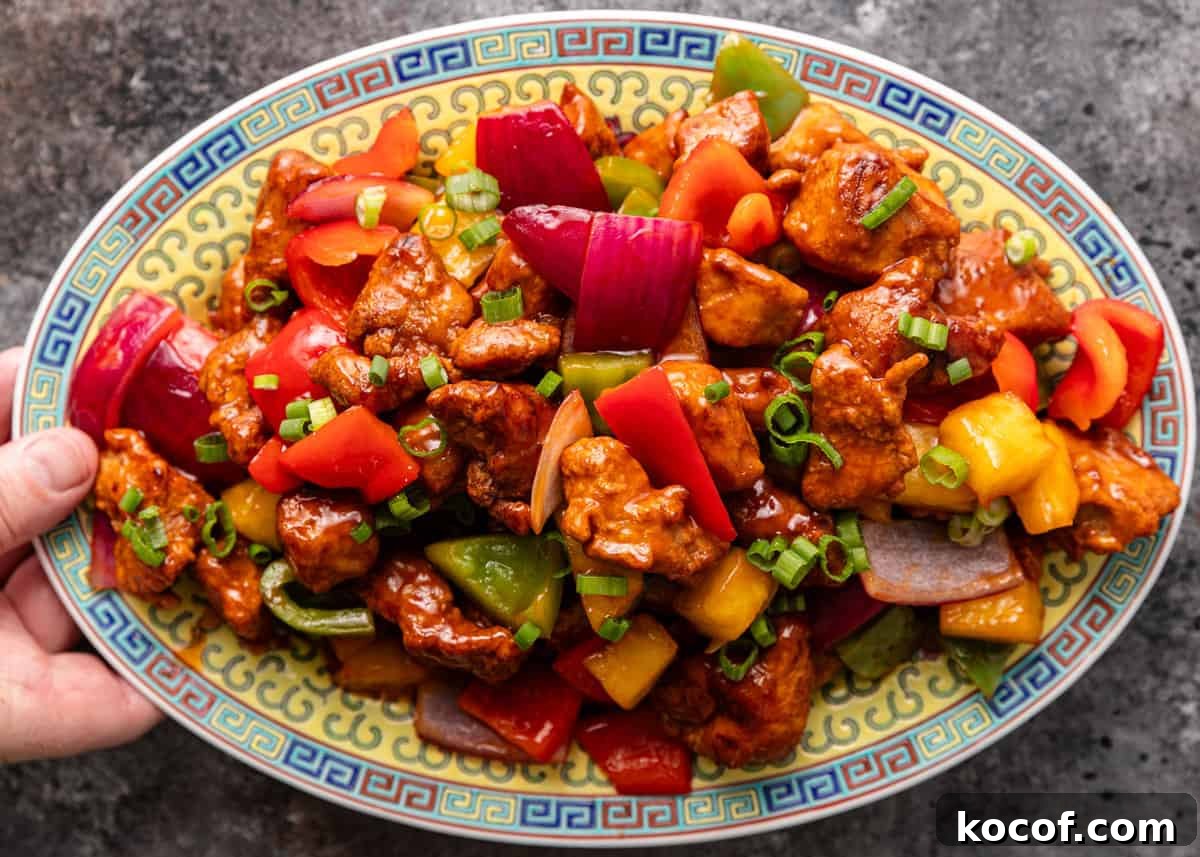 overhead: a hand holding a large platter of sweet and sour pork stir fry