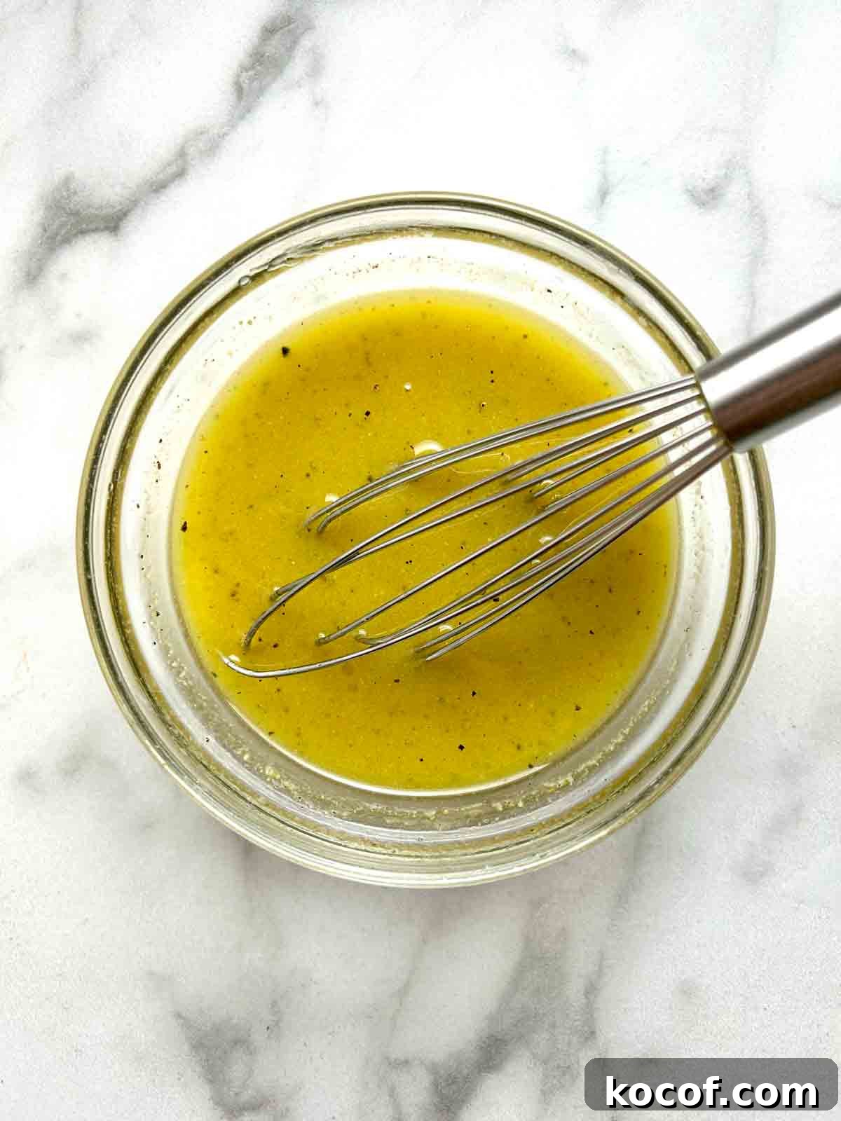 lemon dressing being whisked in small bowl.