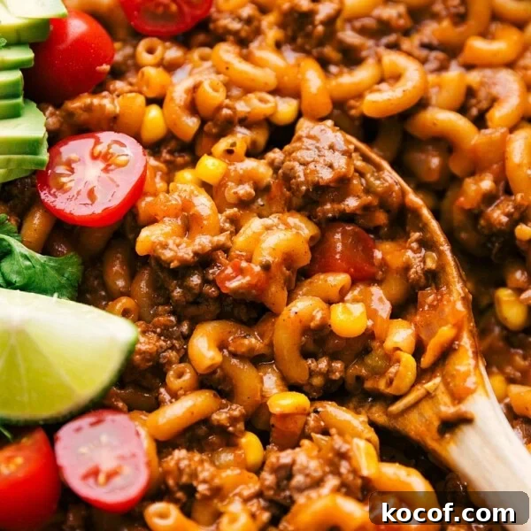 Slow-Cooked Shredded Beef Tacos with Tangy Salsa Verde 6 Spoon scooping up cheesy taco pasta with visible cheese and seasoned meat.