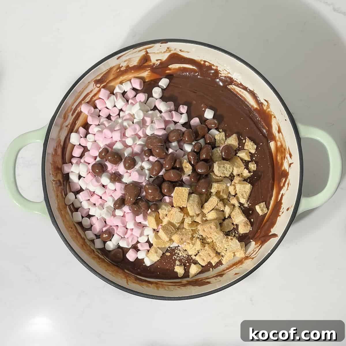 Adding the marshmallows, cookies and chocolate to the rocky road fudge mixture.