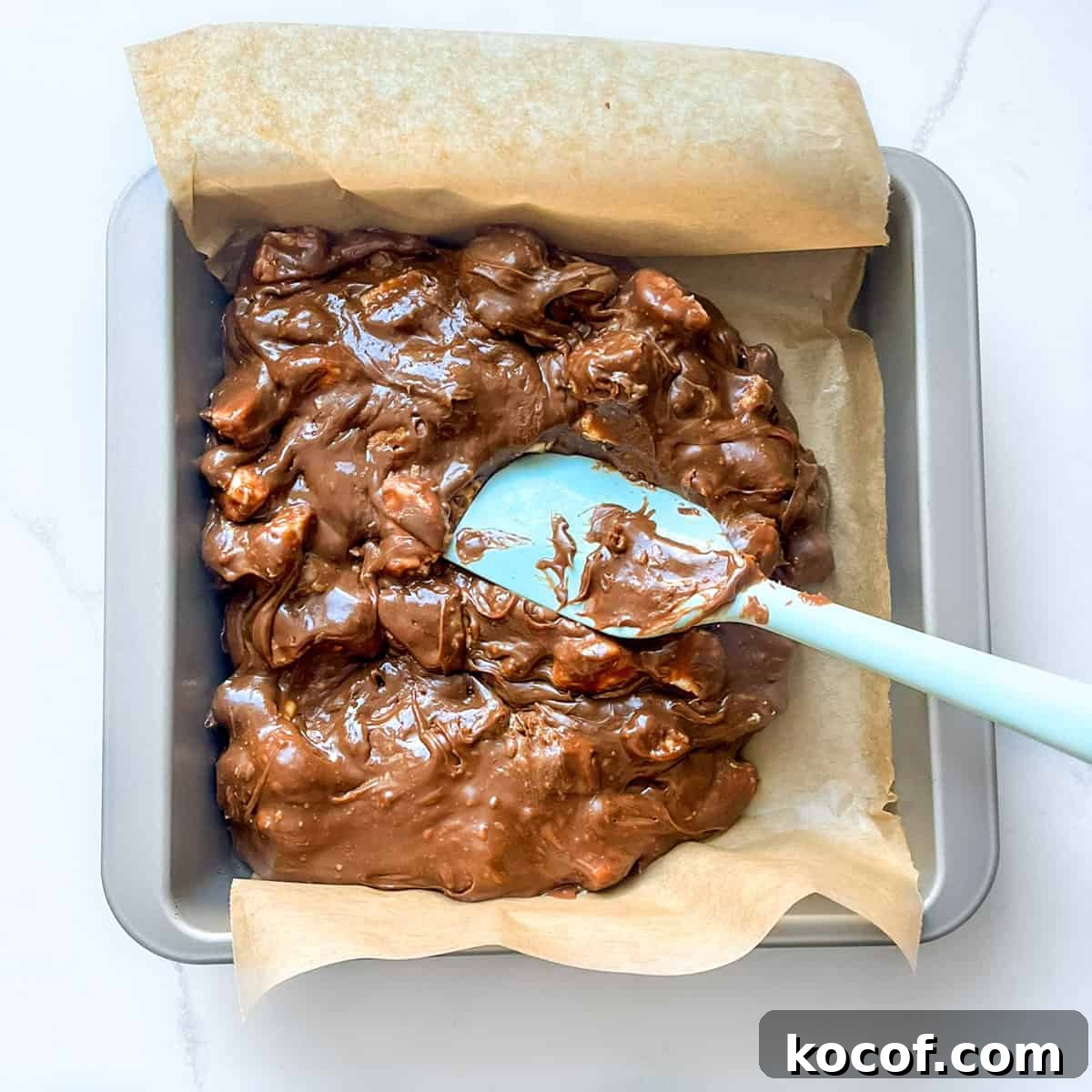 Spreading the fudge mixture in the tin with a spatula.
