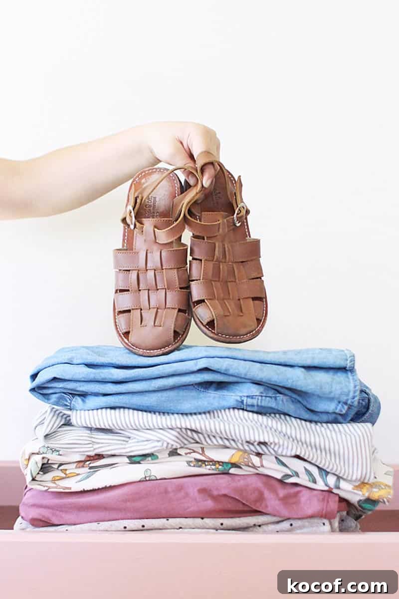 a neat pile of matching pastel dresses for girls and a pair of brown leather shoes