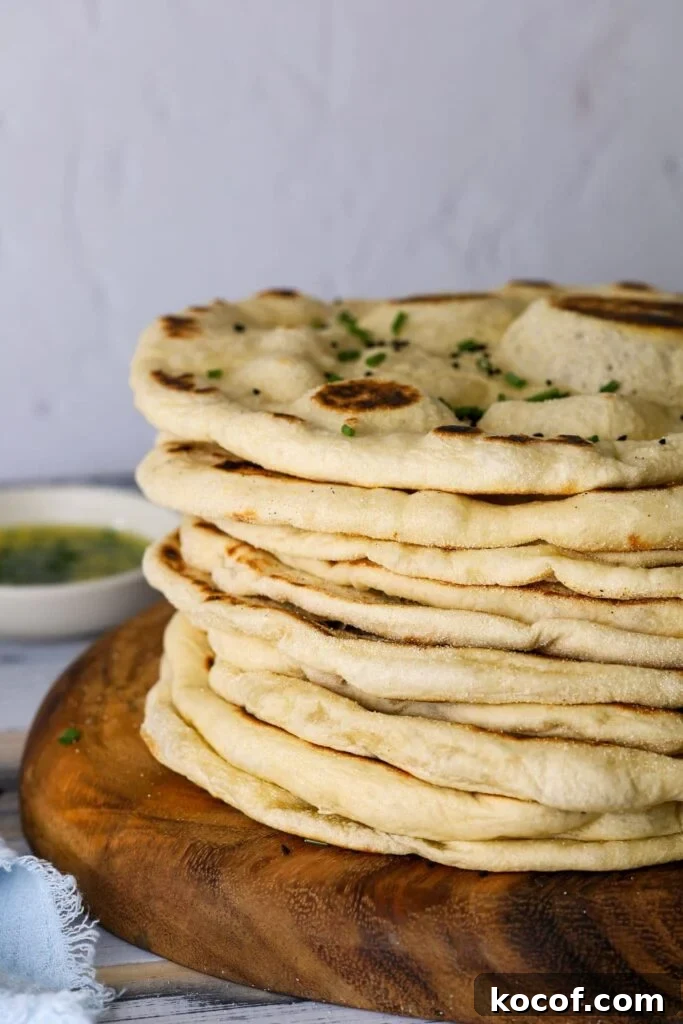 Crispy Sourdough Flatbread Recipe for Homemade Sandwiches 2 A stack of sourdough flatbreads on a round wooden board. There is a small dish of garlic butter in the background.