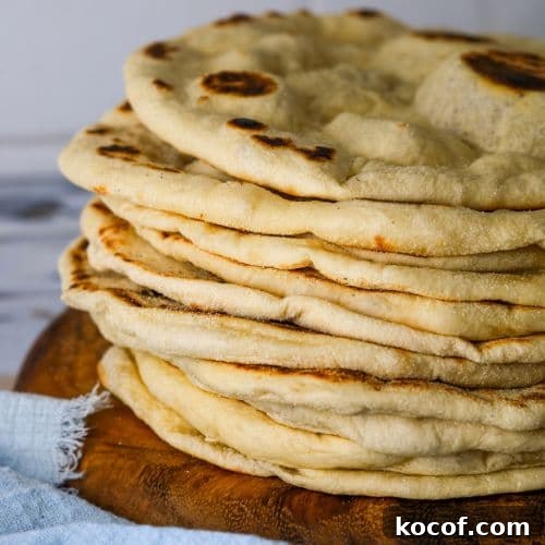 Crispy Sourdough Flatbread Recipe for Homemade Sandwiches 7 A stack of sourdough flatbreads on a round wooden board.