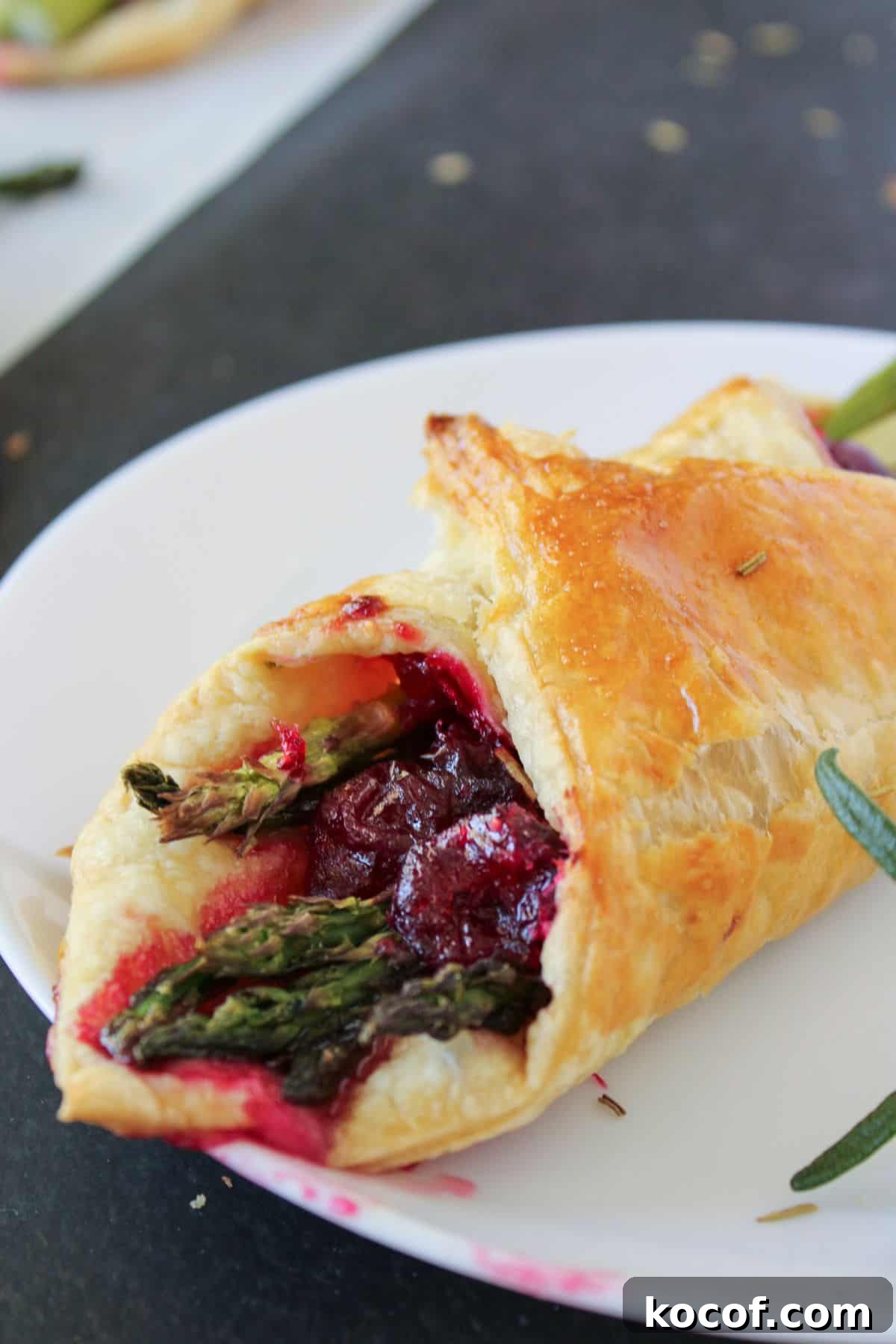 Crispy Puff Pastry-Wrapped Asparagus Recipe 2 Asparagus and cranberry inside puff pastry on a plate.