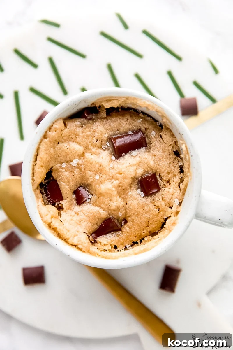 Overhead view of a chocolate chip mug cake next to a gold spoon.