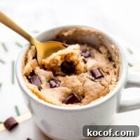 Close up of a spoon resting in a vegan chocolate chip mug cake.
