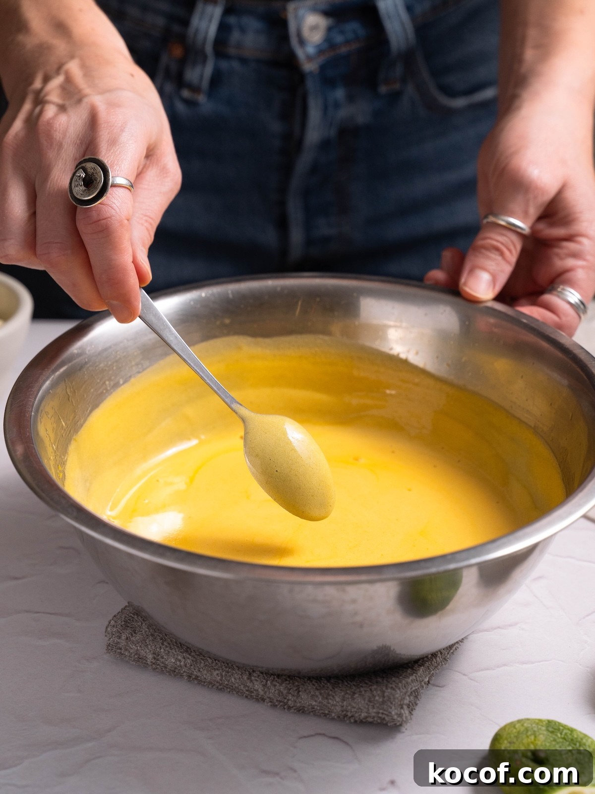 Fresh homemade mango curd coating the back of a spoon
