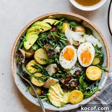 salad with eggs, avocado, potatoes, and bacon on a plate