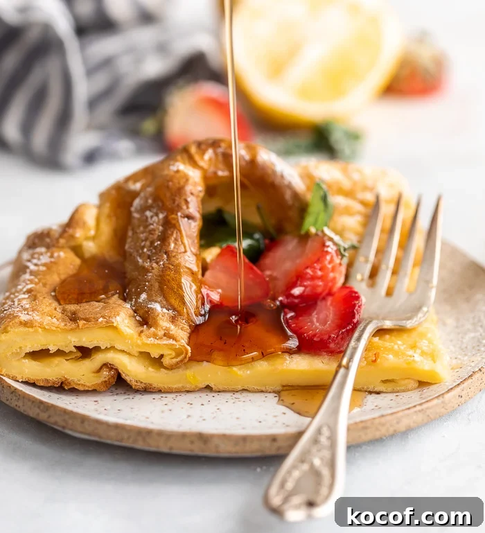 A picture of a slice of a German pancake on a plate topped with strawberries 