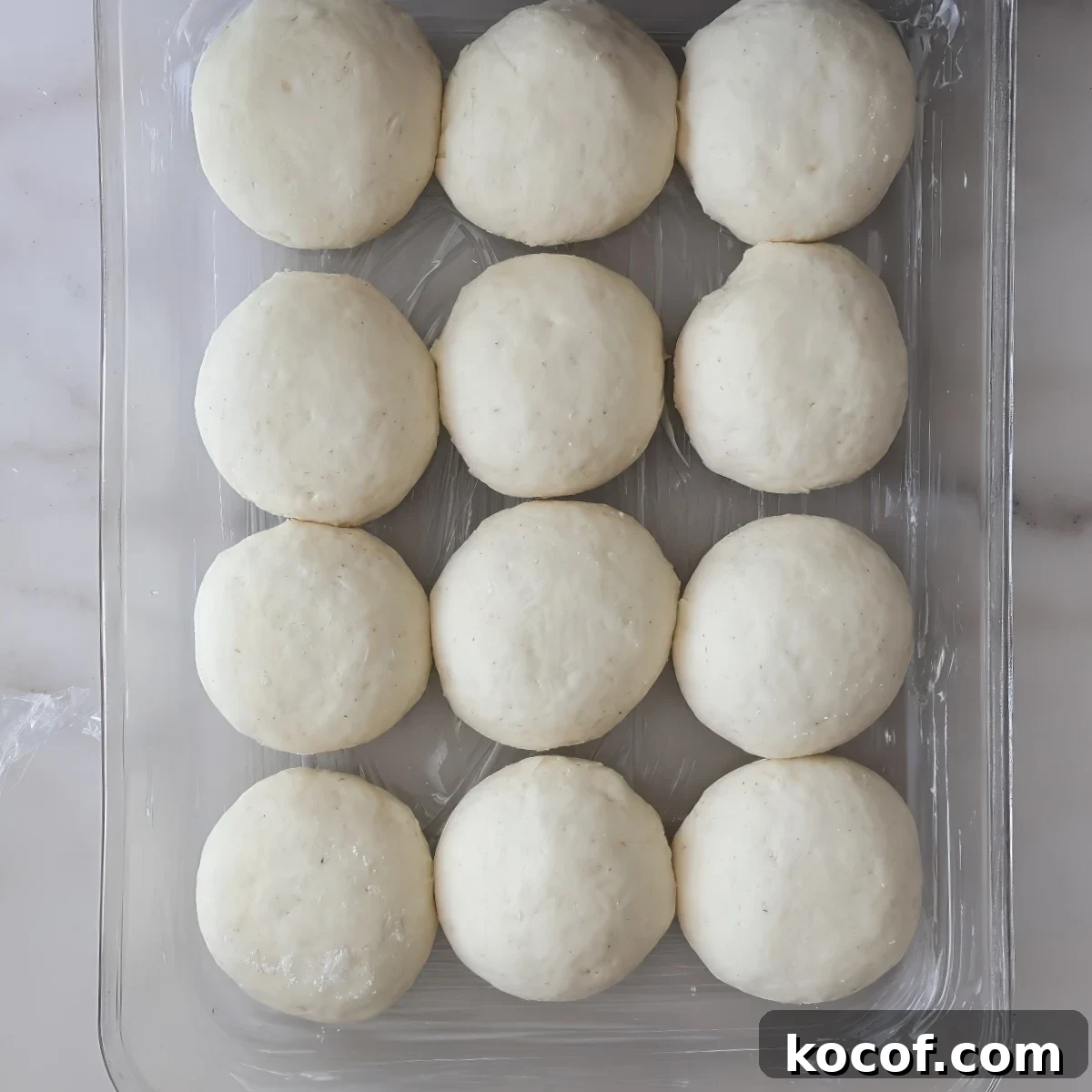 risen round rolls in glass rectangular pan.