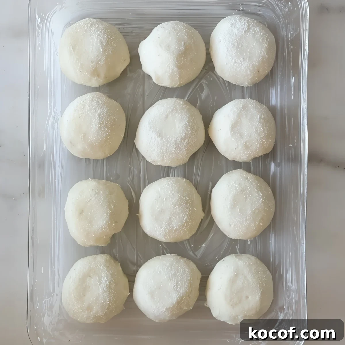 unrisen round shaped rolls in glass pan.