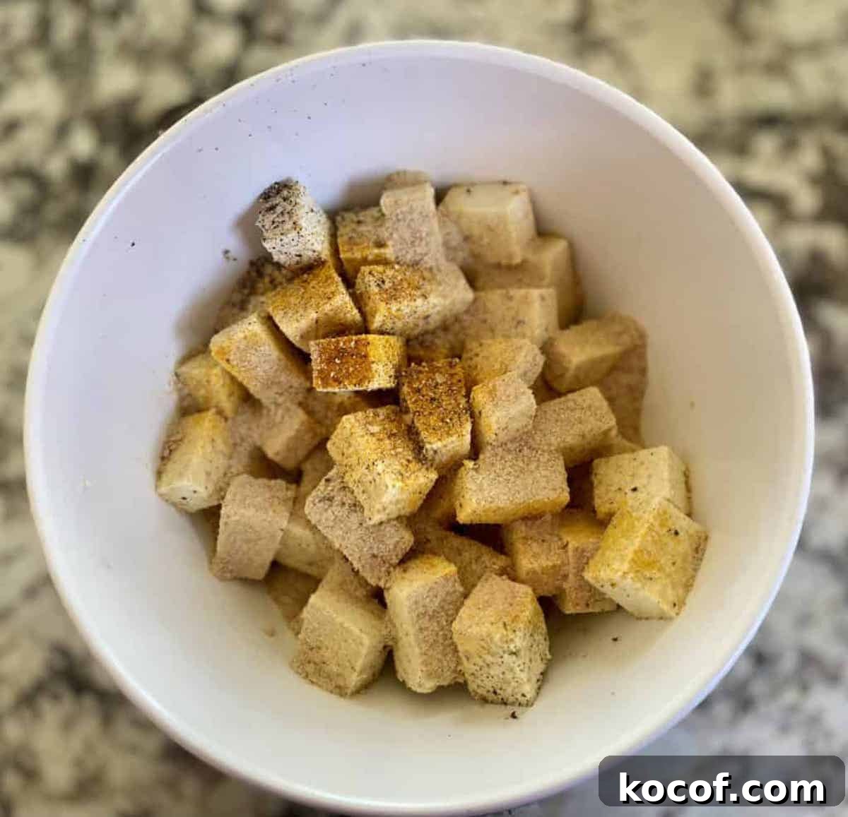 Hearty Vegan Breakfast Bowl with Quinoa, Avocado & Tofu 3 Tofu in a bowl mixed with nutritional yeast, turmeric, and pepper.