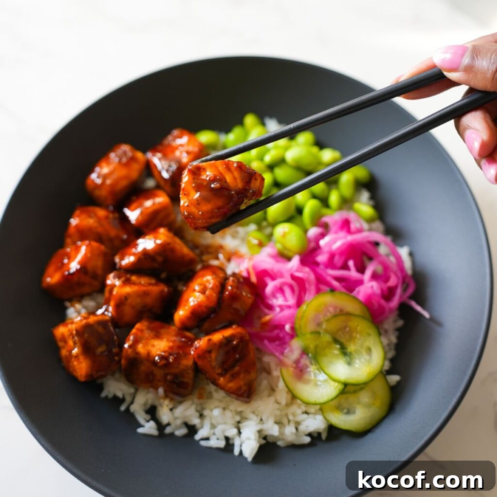 Teriyaki salmon bowl with close up of salmon on chopstick.