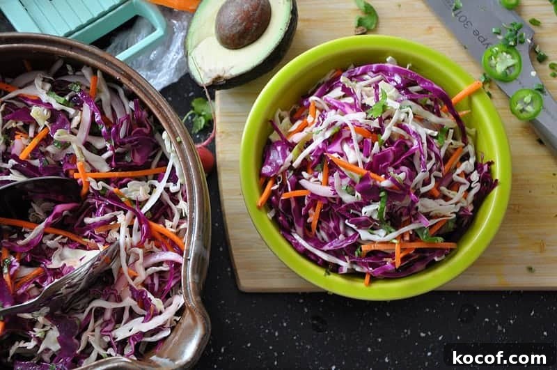 22 Delicious Easter Dinner Ideas That Aren’t Ham 12 Two bowls of cilantro lime coleslaw with a half of avocado sitting on a cutting board next to the bowls and a knife on one side.