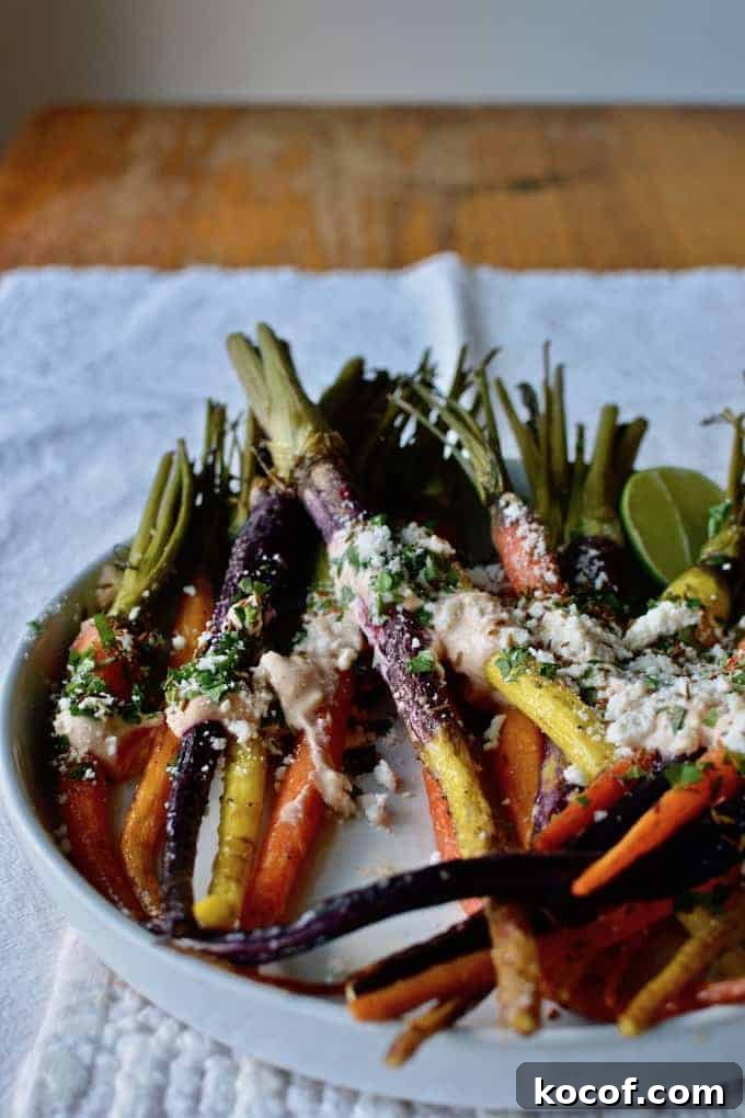 22 Delicious Easter Dinner Ideas That Aren’t Ham 15 A white plate with rainbow carrots that have been roasted sitting on top with cream and cheese and a lime sitting near by.
