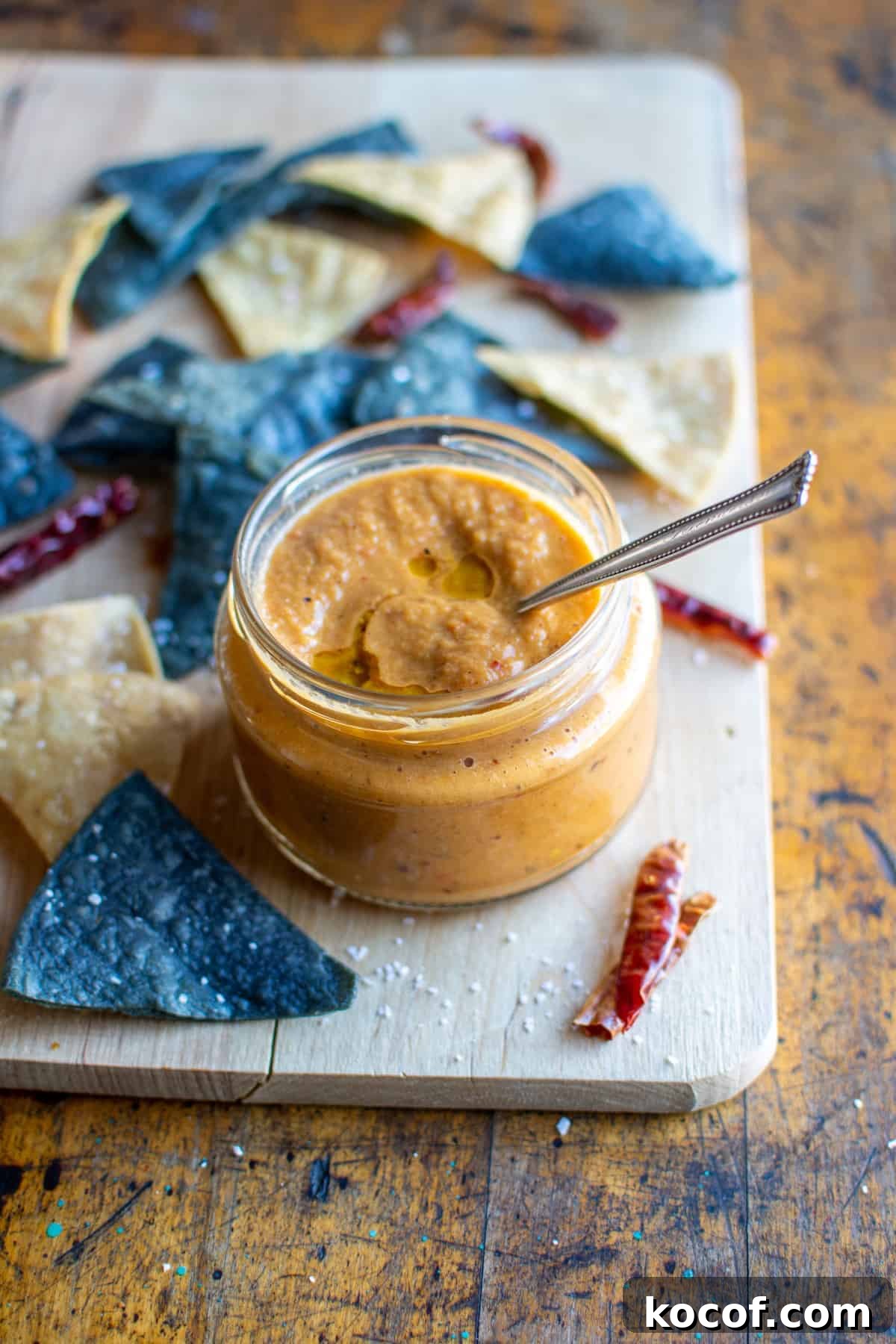 22 Delicious Easter Dinner Ideas That Aren’t Ham 3 A bowl of arbol Chile salsa sitting on a wood cutting board with a spoon in one side and a few colorful tortilla chips around it.