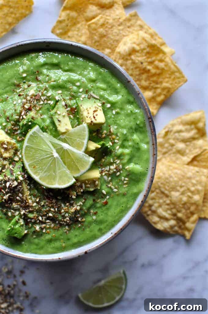 22 Delicious Easter Dinner Ideas That Aren’t Ham 5 Green tomatillo salsa verde in a bowl on a marble table with seeds on top and lime wedges. Several tortilla chips are near by.