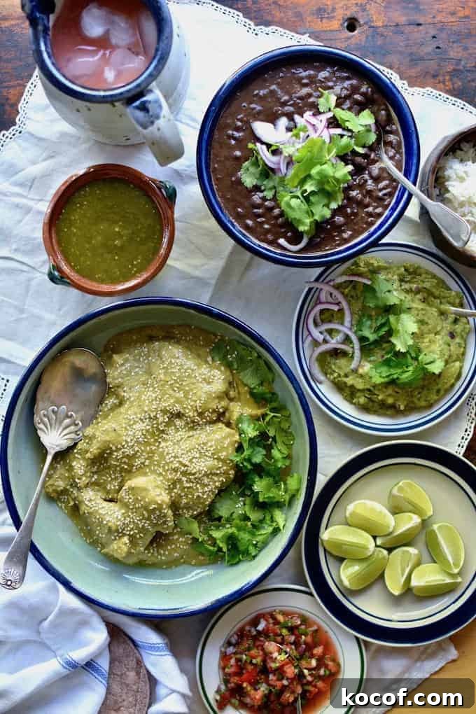 22 Delicious Easter Dinner Ideas That Aren’t Ham 6 A dish of green mole chicken sitting on a table surrounded by a dish of black beans, guacamole, salsa verde, lime wedges.
