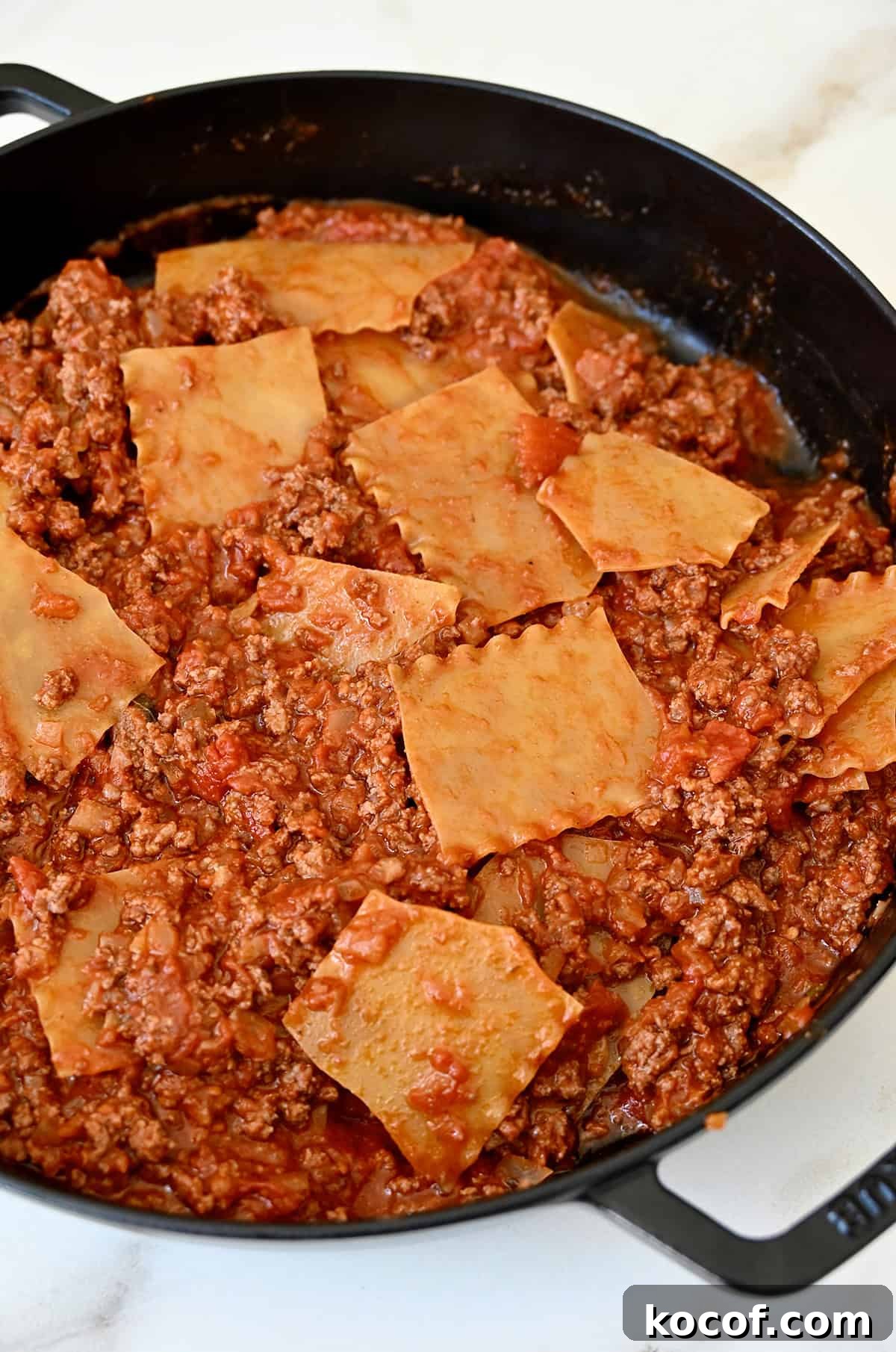 One-Pan Skillet Lasagna Recipe for Quick Weeknight Dinners 8 Pieces of lasagna noodles mixed into bolognese sauce in a large skillet.