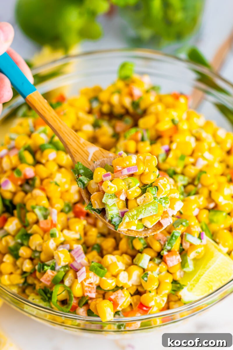 scoop of tex-mex corn salad on a wooden spoon over the bowl