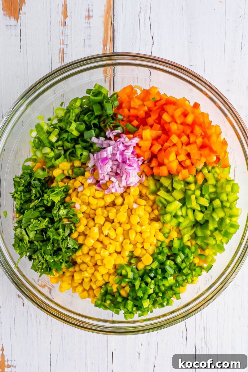 corn, green onion, bell peppers, jalapeno, red onion, and cilantro in a large glass bowl
