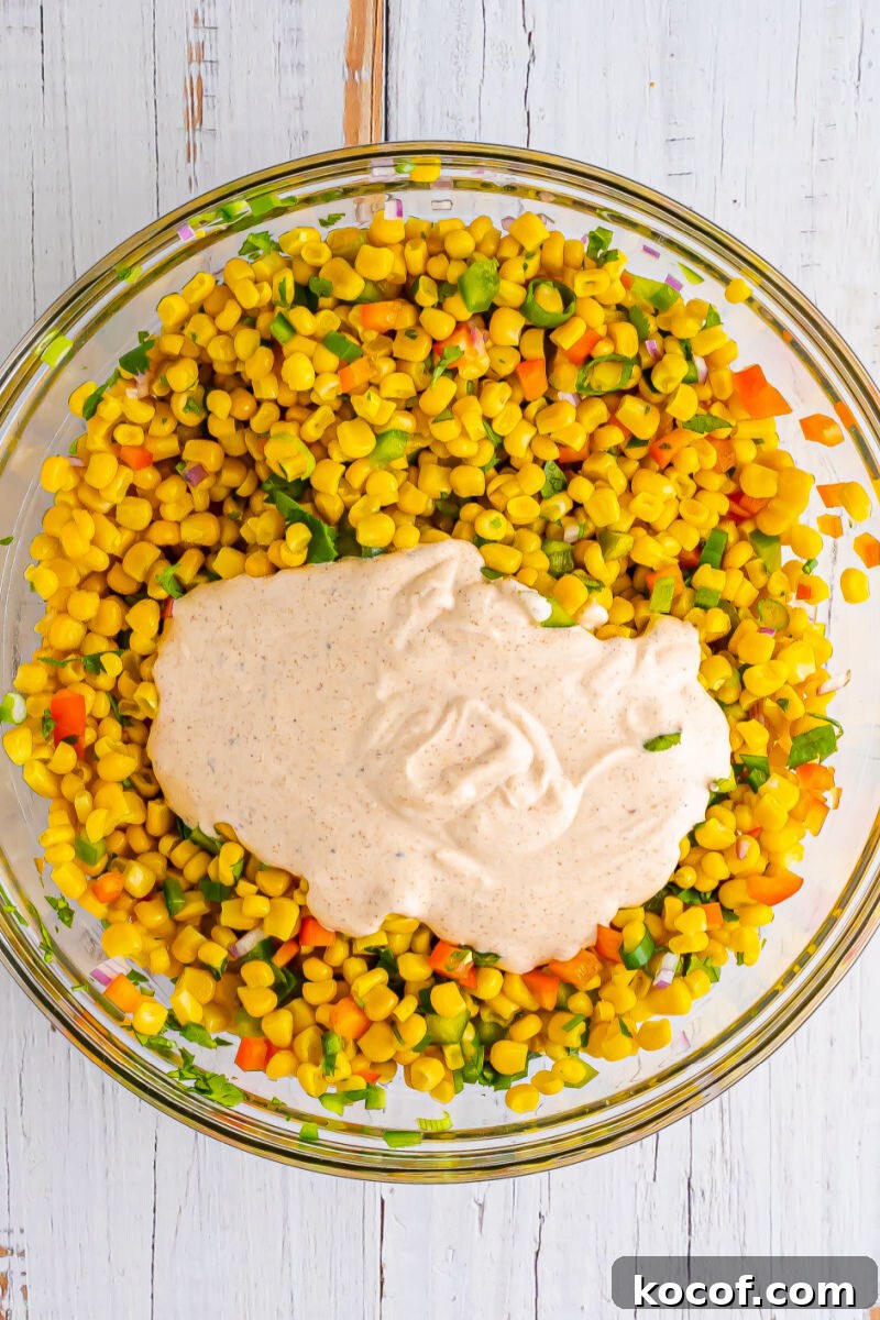tex-mex dressing poured over corn salad veggies in a large bowl