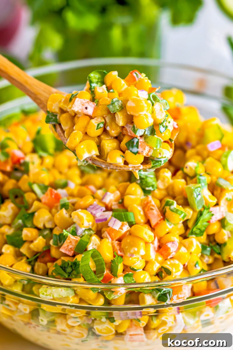close up of a spoonful of tex-mex corn salad over the bowl