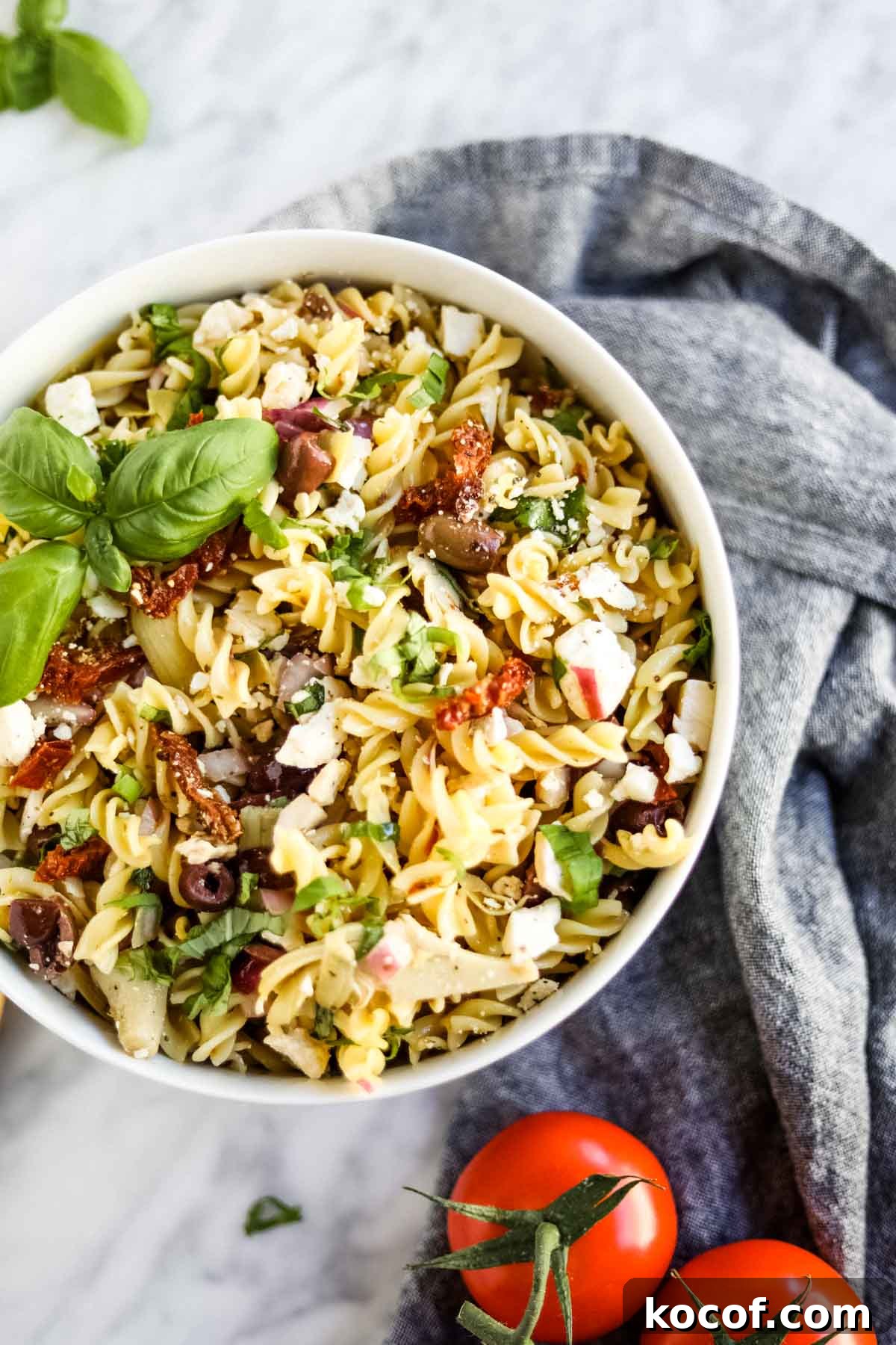 20 Delicious Side Dishes to Serve with Sliders 13 Pasta salad with Italian ingredients in bowl flatlay.