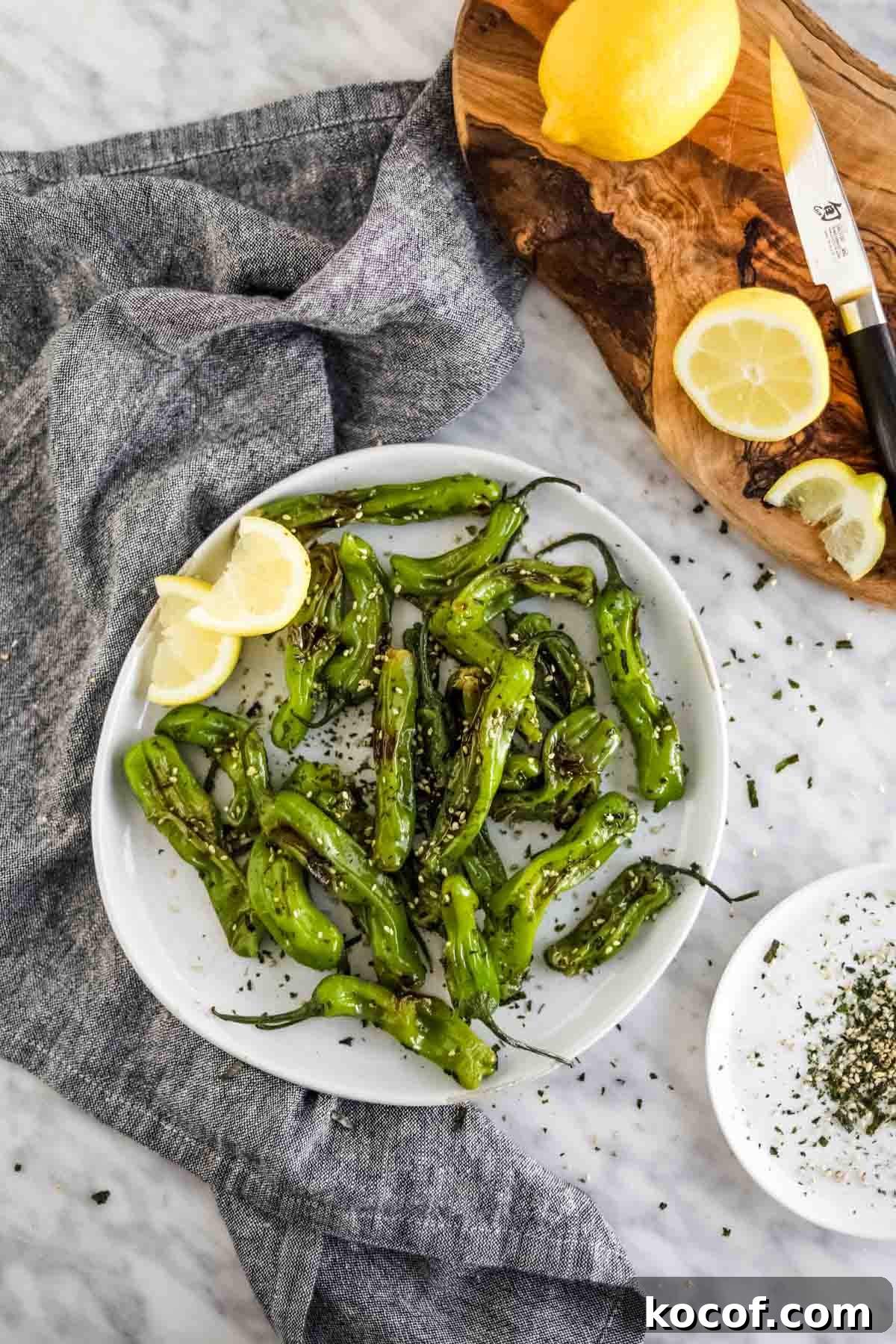 20 Delicious Side Dishes to Serve with Sliders 16 Shishito Peppers with furikake and lemon on plate flatlay.