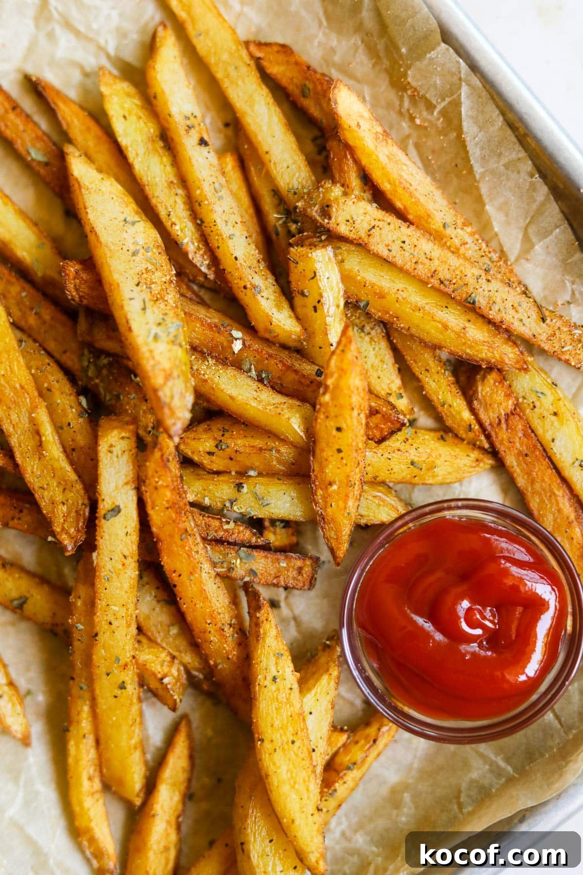 20 Delicious Side Dishes to Serve with Sliders 17 Classic seasoned french fries with garlic powder, dried basil, paprika, and ketchup on a baking sheet with parchment paper.