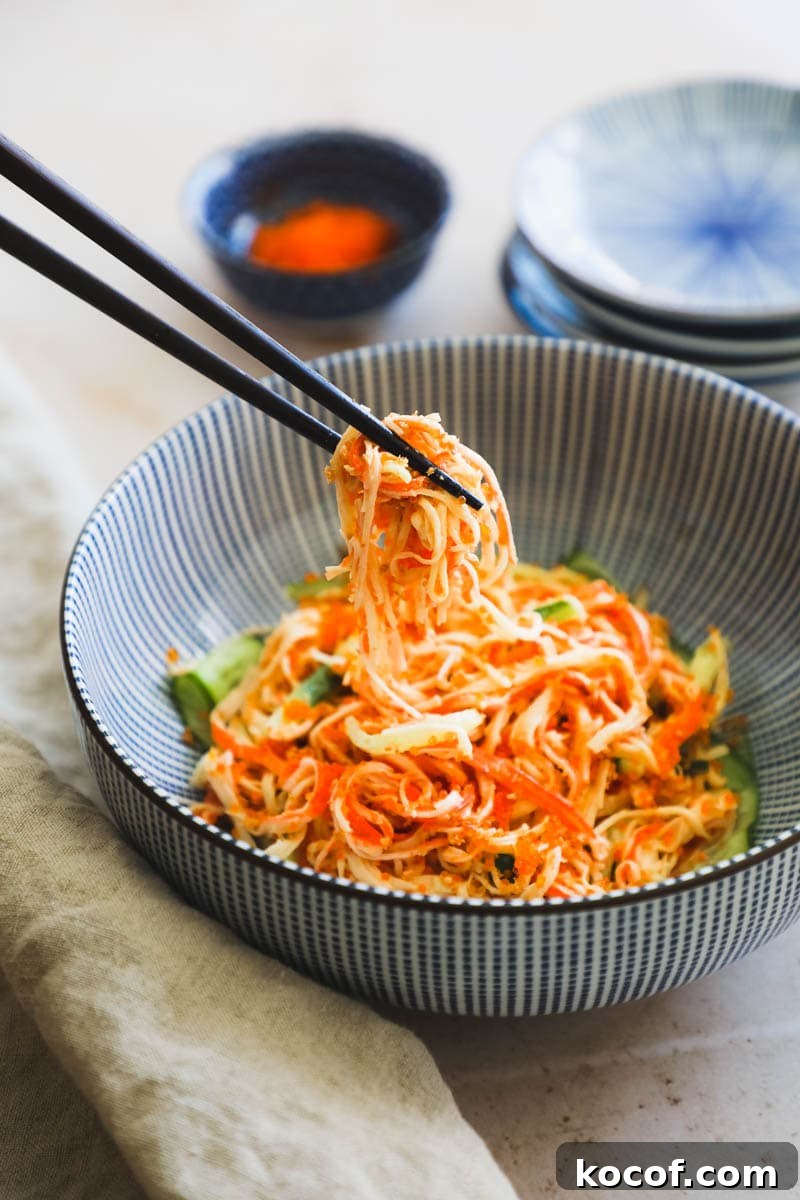 20 Delicious Side Dishes to Serve with Sliders 21 Chopsticks lifting a bite of Spicy Kani Salad out of a blue Japanese bowl.