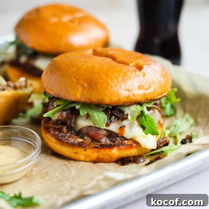 Wagyu beef cheeseburger with arugula, gruyere, grilled onions, and wasabi mayo on parchment paper with a Mexican coke.