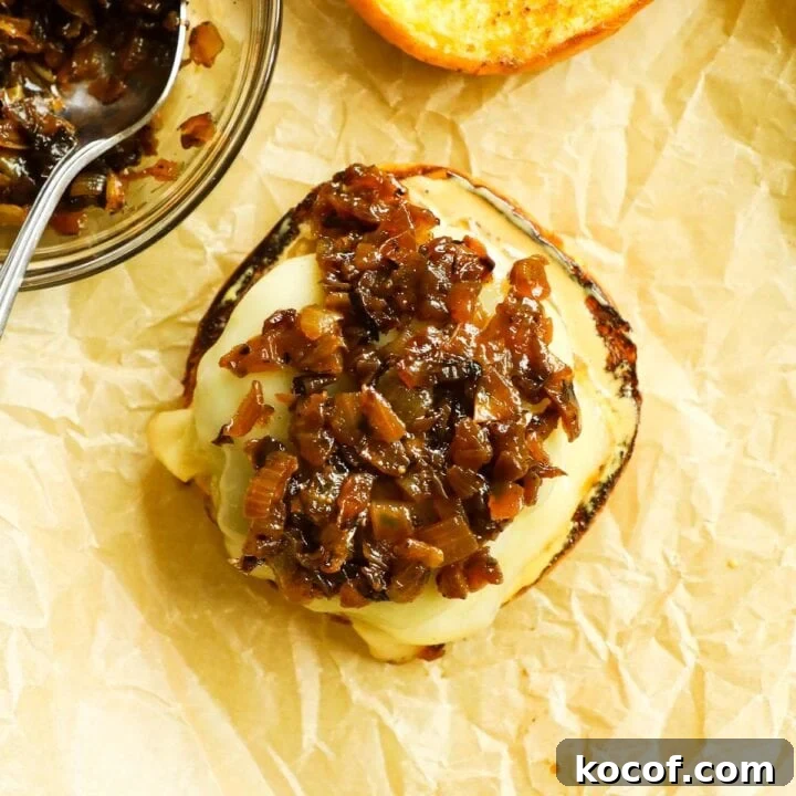 Burger topped with caramelized onions on a baking sheet with parchment paper.