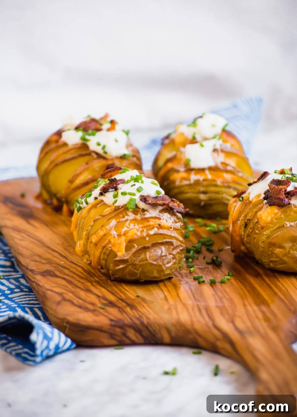 20 Delicious Side Dishes to Serve with Sliders 5 Bacon Cheddar Hasselback Potatoes on cutting board.