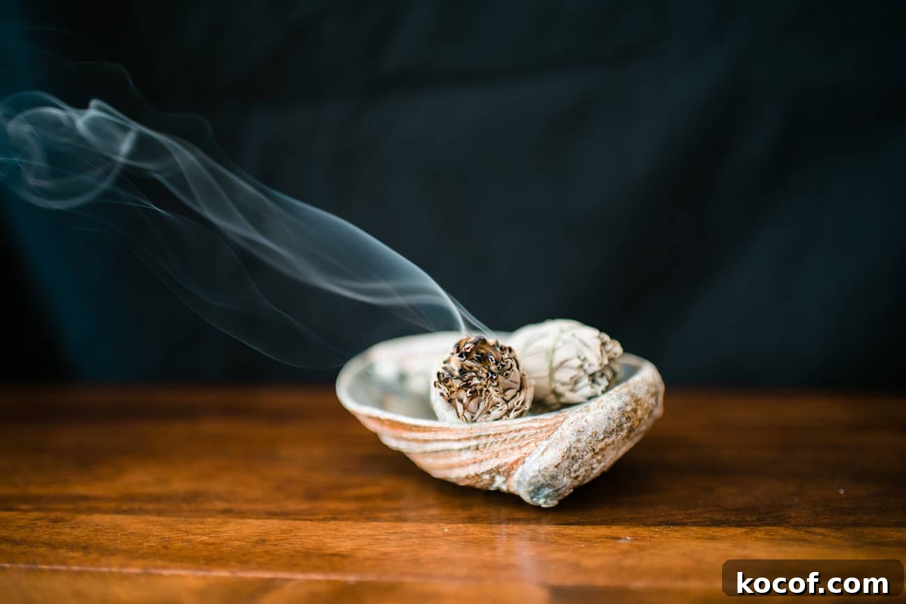 Smudge Your Home for Protection: Simple Ritual and Prayer 7 Burning white sage smudge sticks in an abalone shell with smoke rising during a home cleansing ritual and smudging prayer.