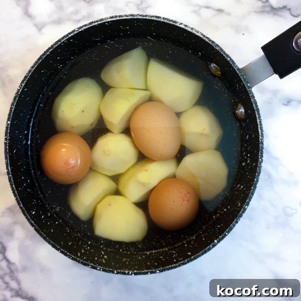 Creamy Potato and Egg Salad Recipe for Picnics & BBQs 5 Eggs and large pieces of potato in a saucepan.