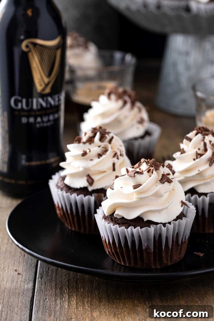 chocolate Guinness cupcakes with whipped cream frosting and chocolate shaving on a black dessert plate