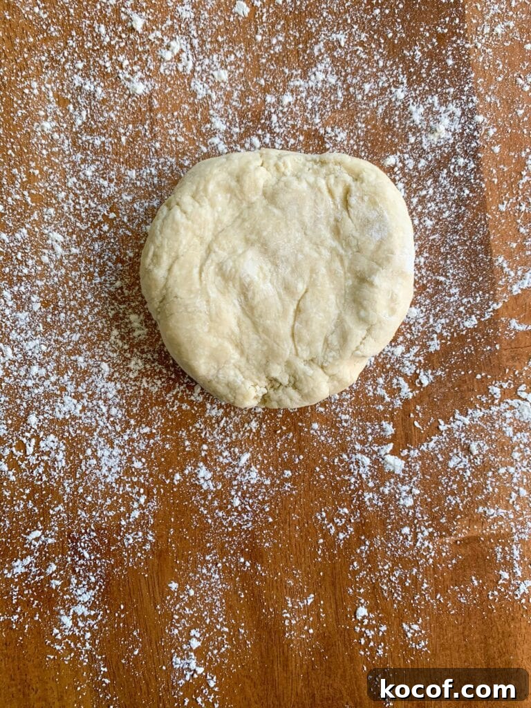 Flaky All-Butter Pie Crust Recipe for Perfect Pastry 12 A disc of pie dough on a flour covered wooden table.