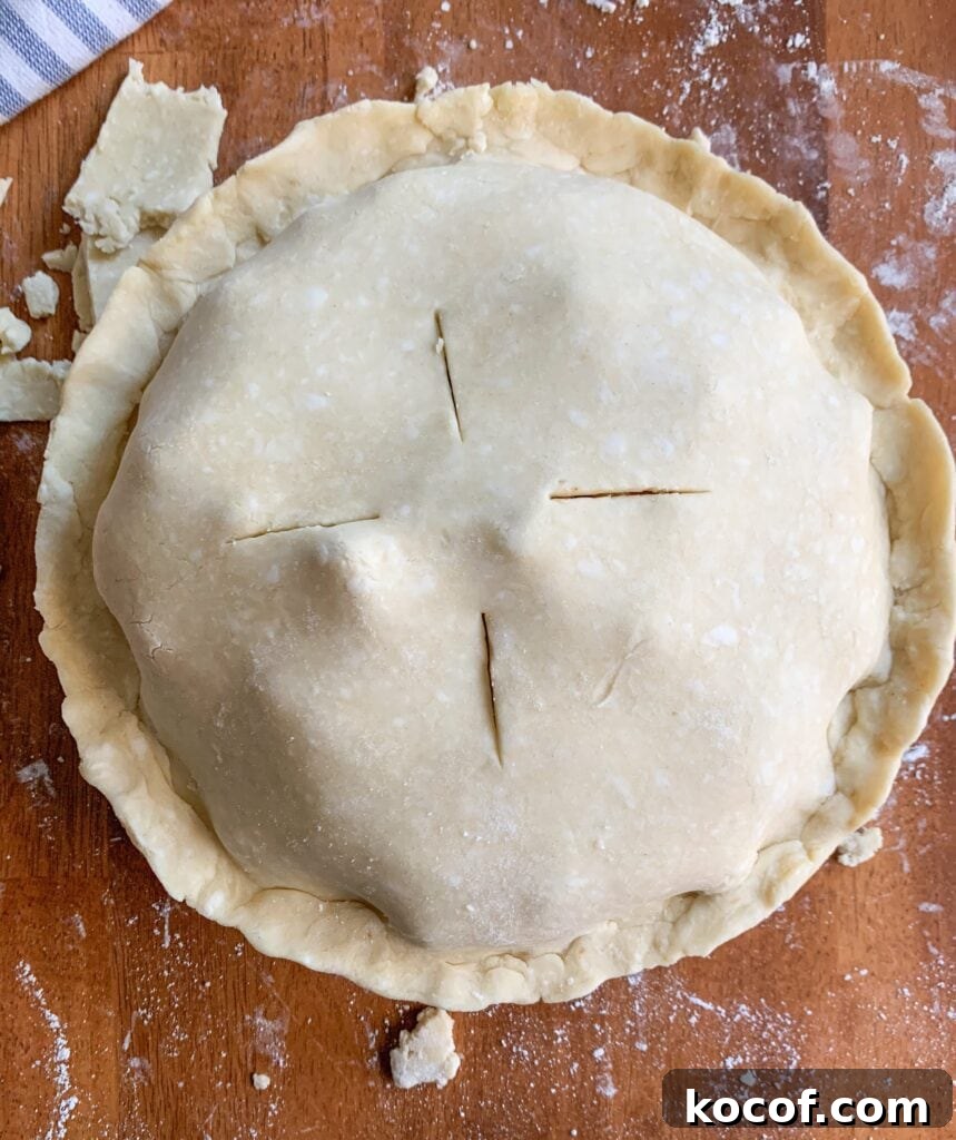 Flaky All-Butter Pie Crust Recipe for Perfect Pastry 7 An image of a raw pie, with a criss cross design cut in the top.