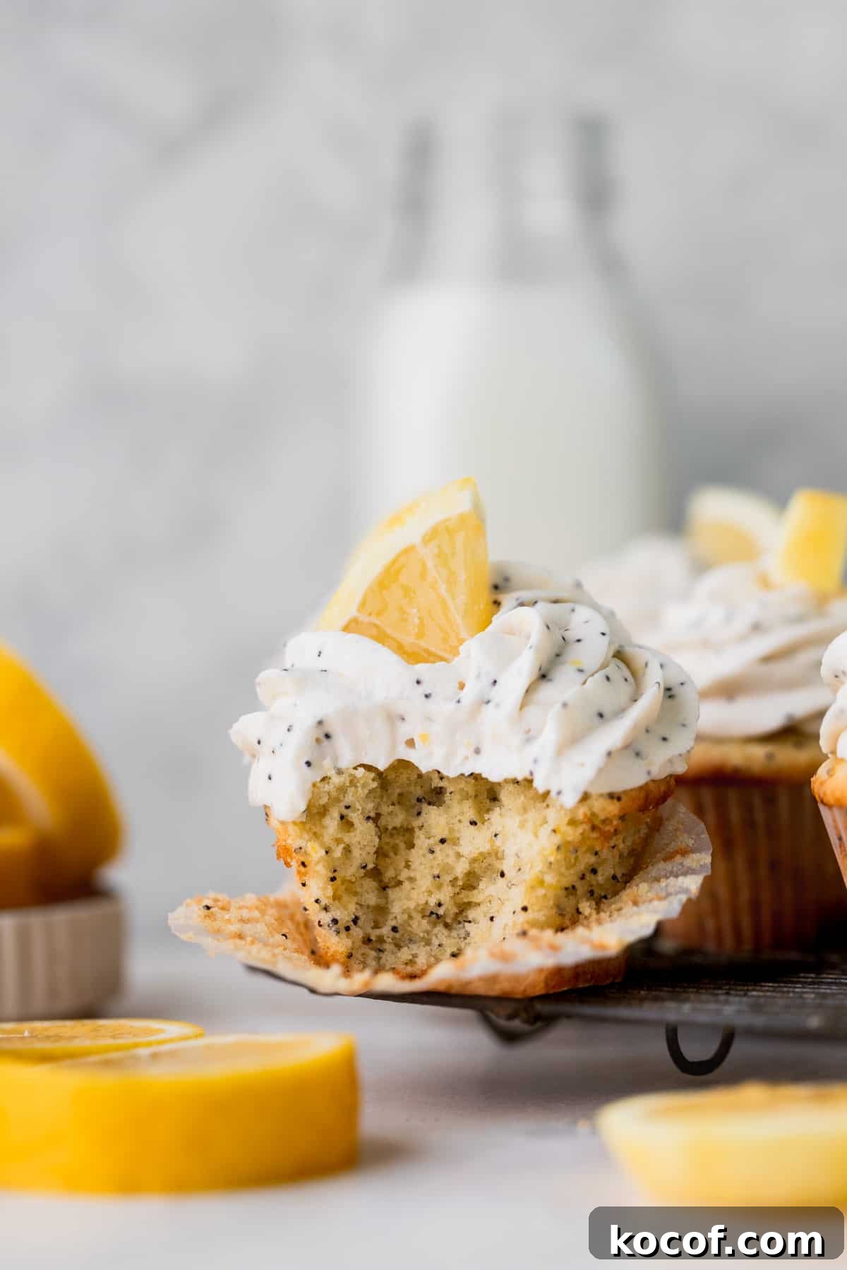 Lemon Poppy Seed Cupcakes with Zesty Glaze and Moist Crumb 3 Bite missing from cupcake on a wire stand.